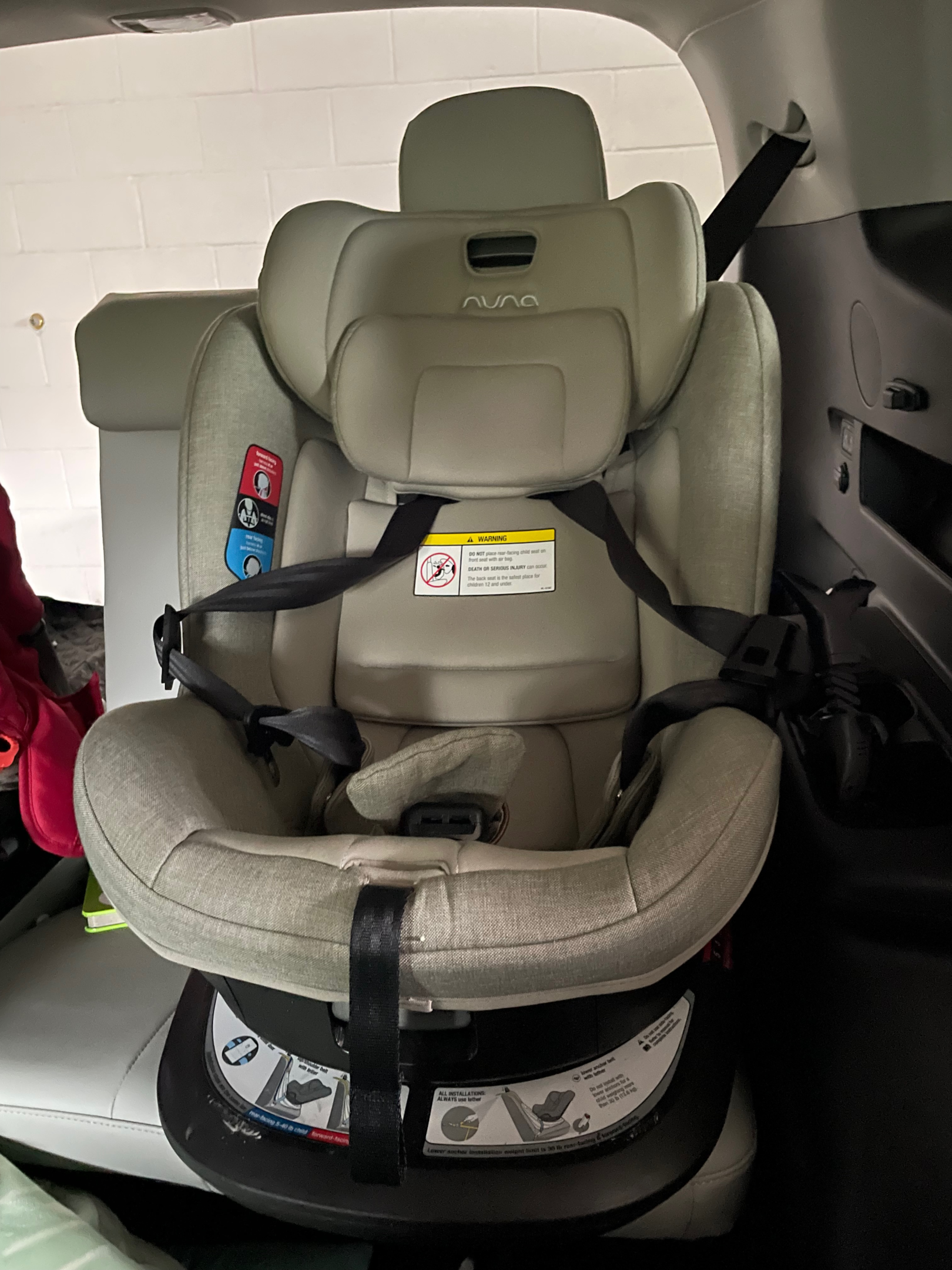 Rotating Nuna child car seat installed in vehicle displaying head rest and other adjustable portions